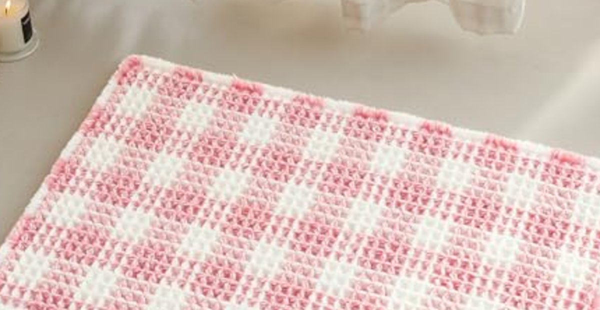 A pink check TYUU bath mat by a sink